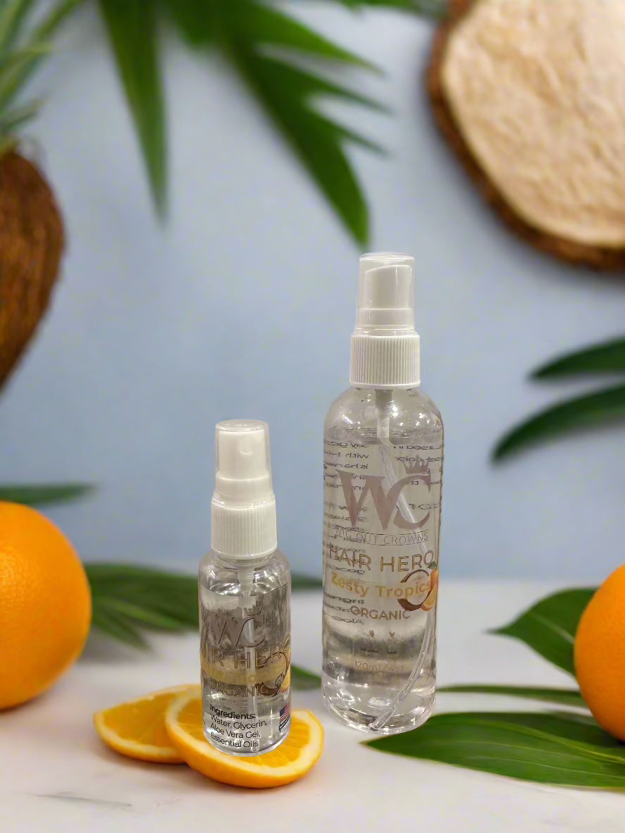 Hair Hero detangler bottles displayed with fresh orange slices, whole oranges, and tropical palm leaves on a light background.